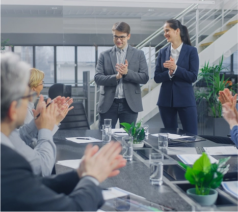 Business colleagues applauding during a presentation in a modern office conference room.