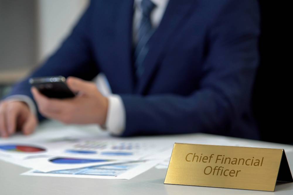 Chief financial officer checking data in annual report, using smartphone, work