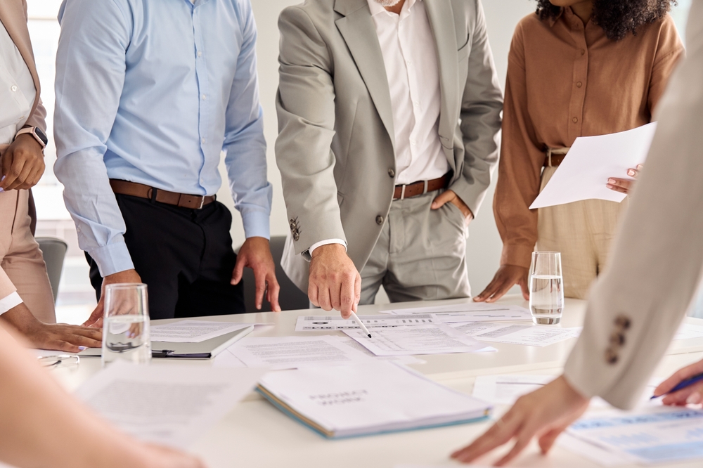 Executive business team people group working with paperwork standing at table, analyzing corporate strategy