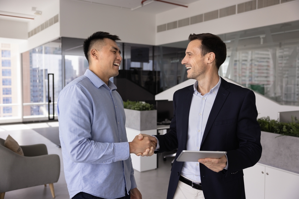 Happy diverse male business colleagues greeting each other with handshake in office space