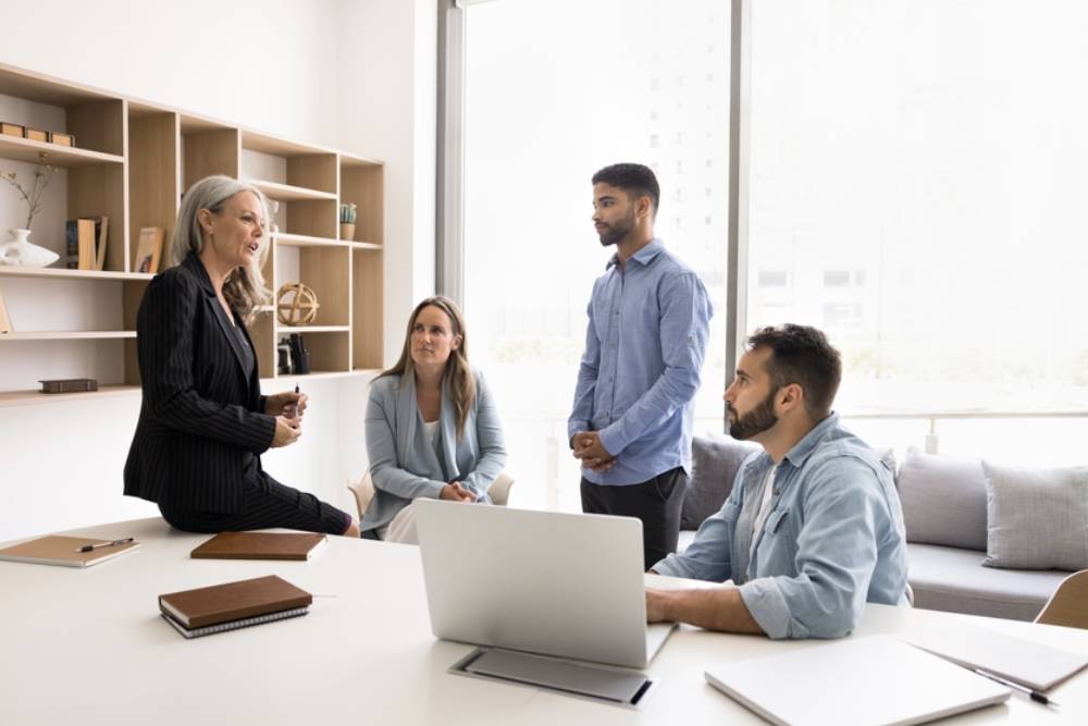Mature woman, company boss engaging in conversation with team, giving instructions, sharing updates